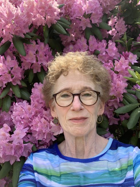 Headshot of Gail Packer standing in front of pink rhododendron flowers